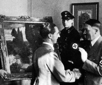 Joseph Goebbels och Adolf Hitler skakar hand framför en plundrad tavla